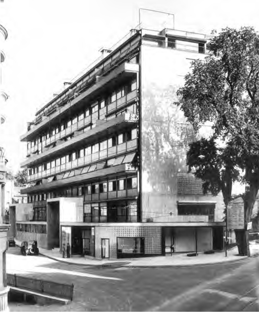 Mehrstöckiges modernes Wohn- und Geschäftshaus an Straßenecke, Fassadenbalkone und großer Baum, Corbusier